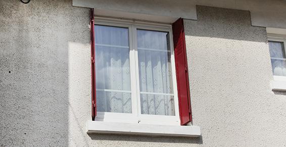 Photo d'une fenêtre fermée et de ses volets bordeaux pliés